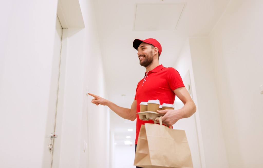 delivery man with coffee and food ringing doorbell