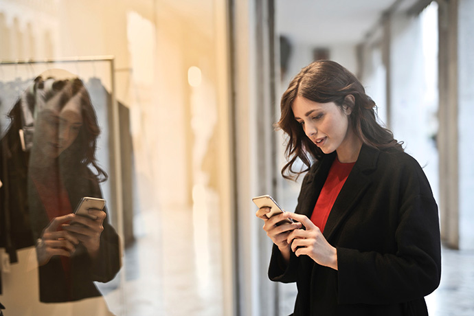 Una usuario con smartphone delante de un escaparate